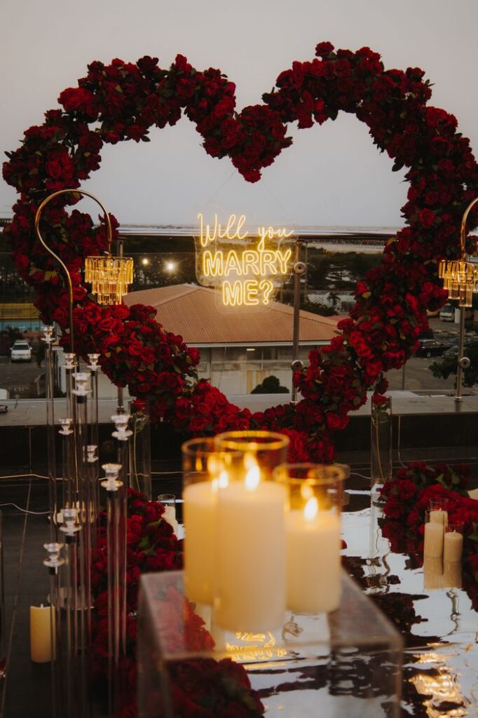 Heart-shaped rose arch with candles for a perfect marriage proposal.